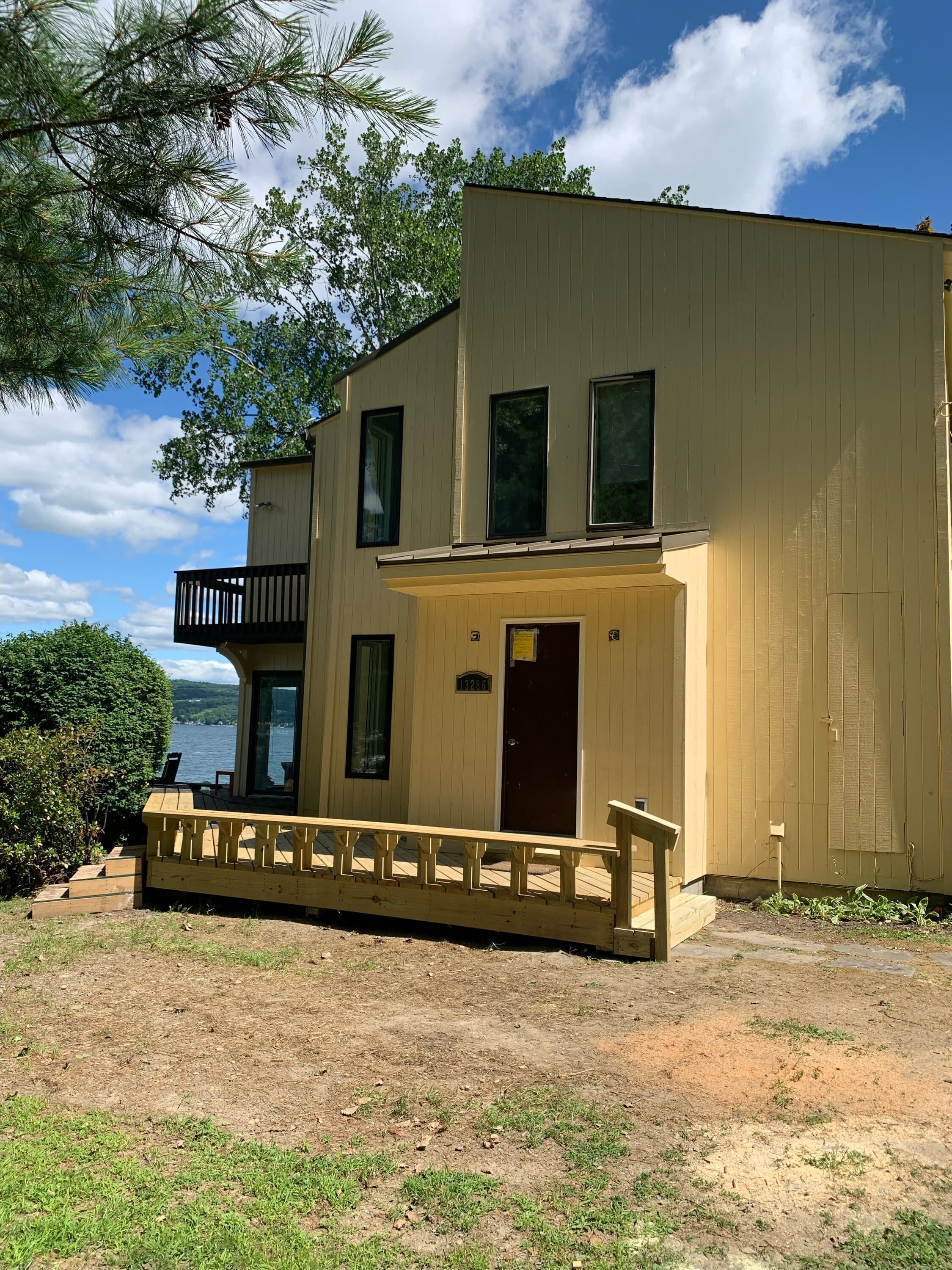 Yellow two-story custom home with deck overlooking Keuka Lake