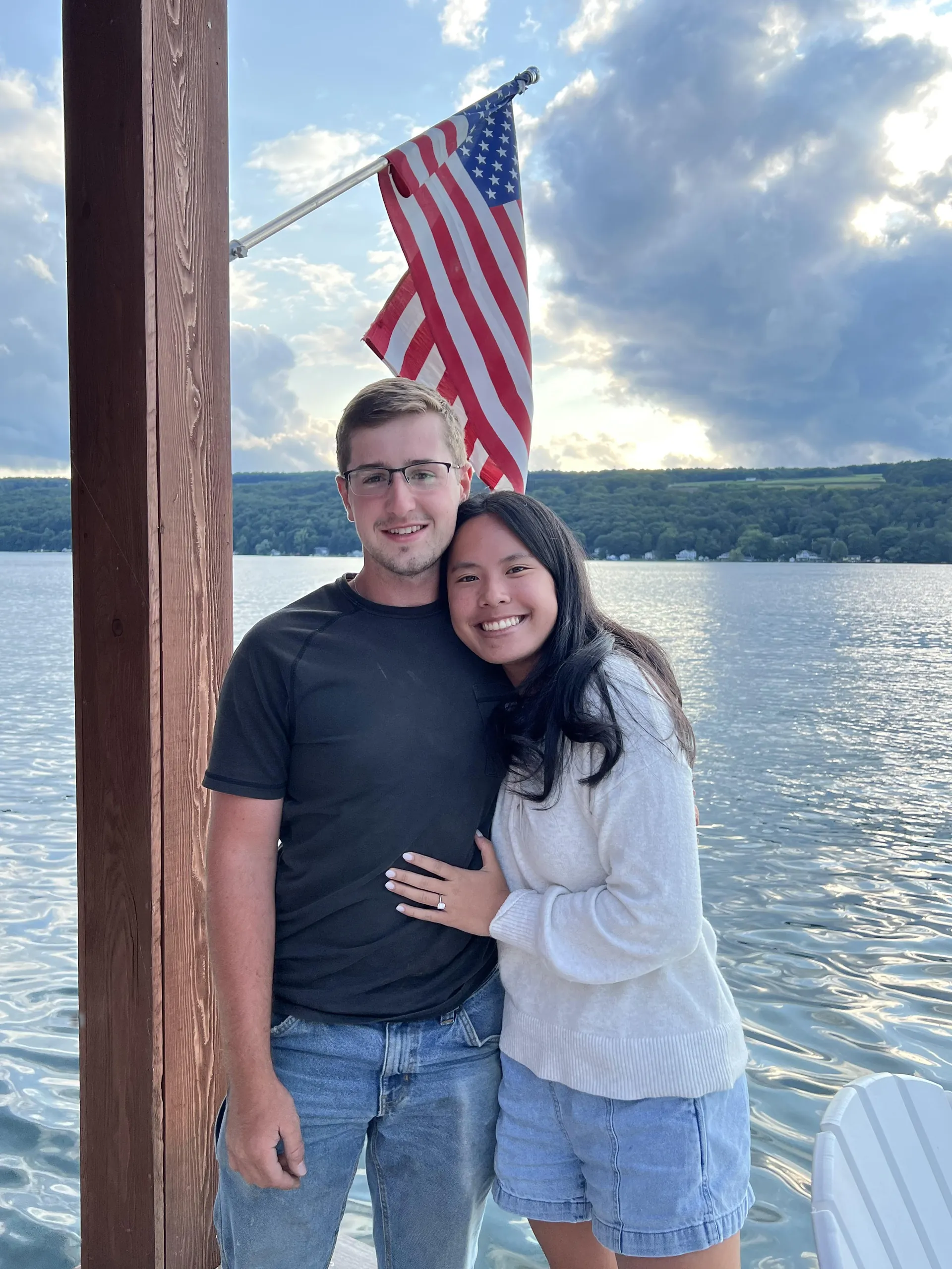 Kyle and Kenna Miller, the owners of Crossroads Construction, together on a dock at Keuka Lake with an American flag