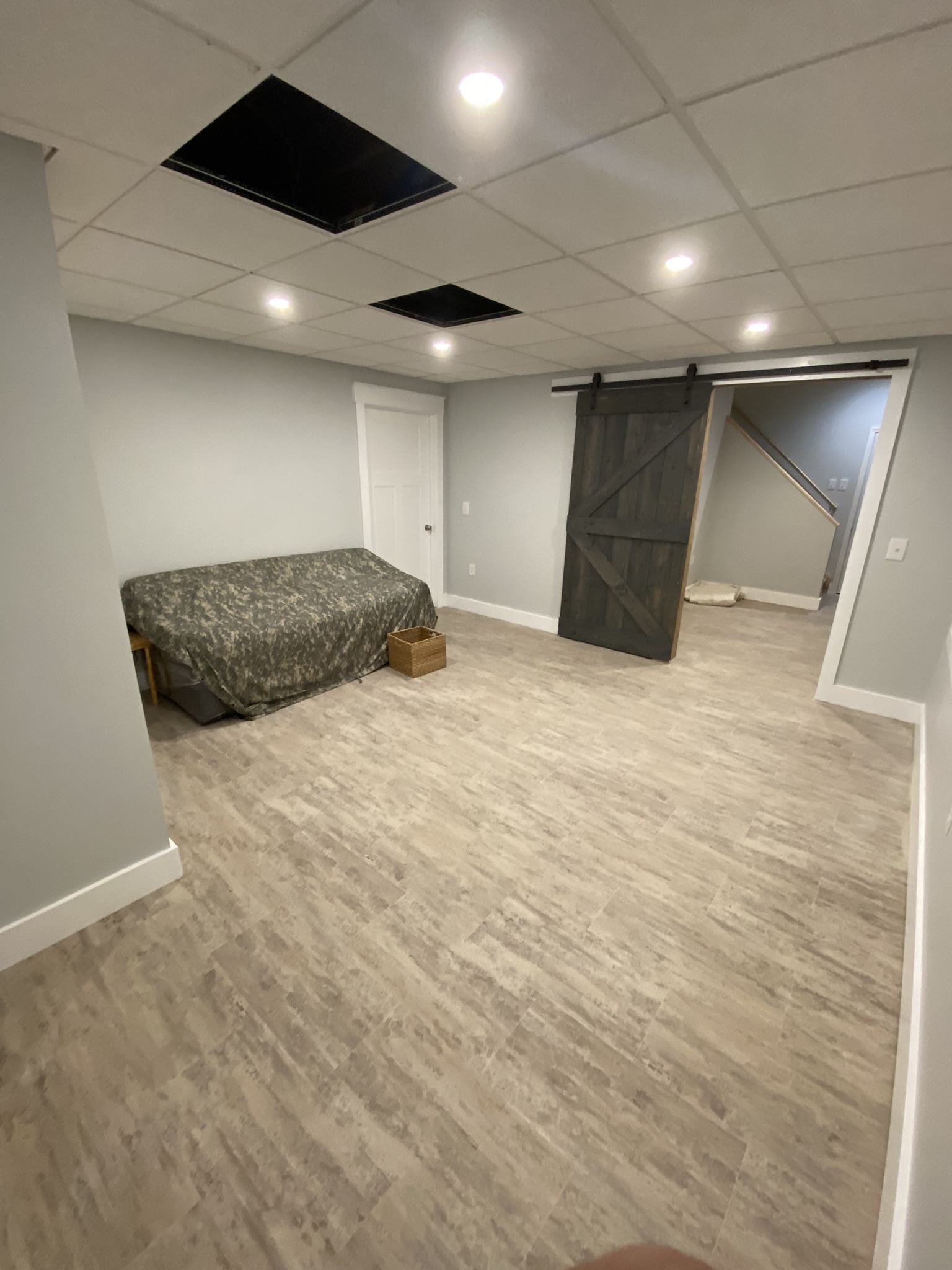 Finished basement with gray flooring, recessed lighting, and sliding barn door