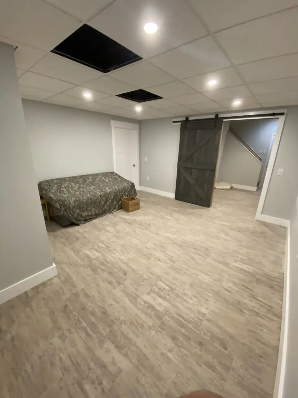 Finished basement with gray flooring, recessed lighting, and sliding barn door