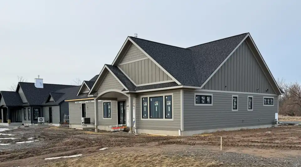 Gray craftsman-style home under construction with dark roof and white trim